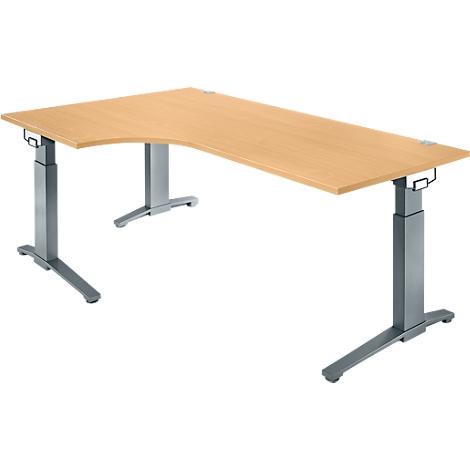 A beige, height-adjustable corner desk with silver legs. The tabletop is L-shaped.