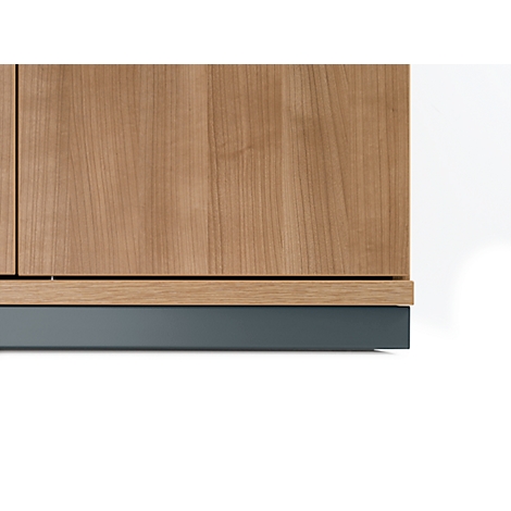 Nahaufnahme einer Holzschrank-Ecke, darunter graue Blende. Struktur des Holzes deutlich erkennbar.