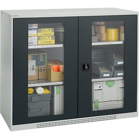 Tool cabinet with glass insert. Tools, screws and packaging are in the compartments. Black frame, white housing.