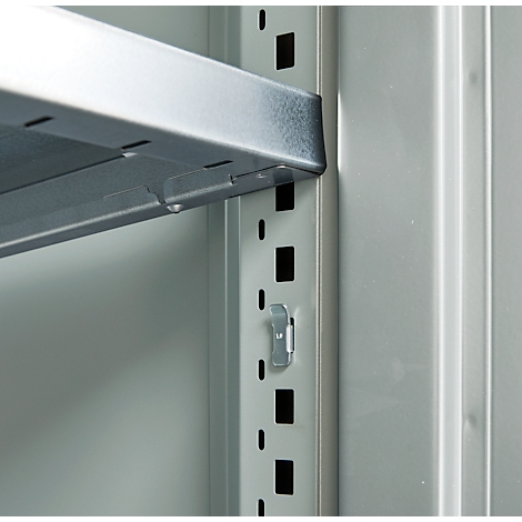 Close-up of a shelving system. A silver shelf is inserted into a holder, next to a series of holes and brackets.