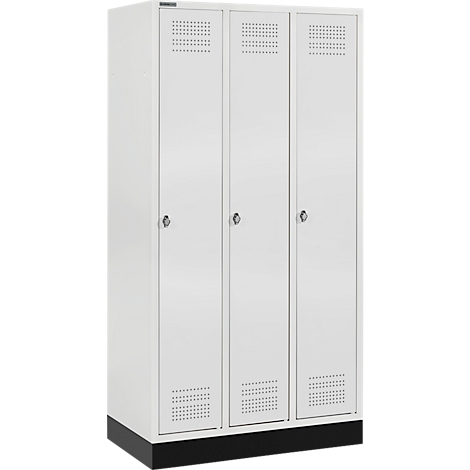 Witte locker met drie deuren, gaten en handgrepen. Zwarte basis. Zicht op een iets verhoogde hoek.