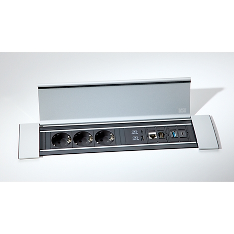 Silberne Tischanschlussbox mit drei Steckdosen, Netzwerk-, USB- und HDMI-Anschlüssen auf grauem Hintergrund.