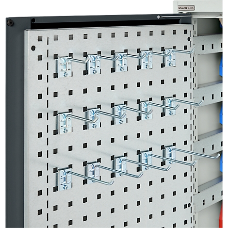 Metallwand mit Lochmuster, darauf Haken montiert. Im Hintergrund ist ein Schrank zu sehen.