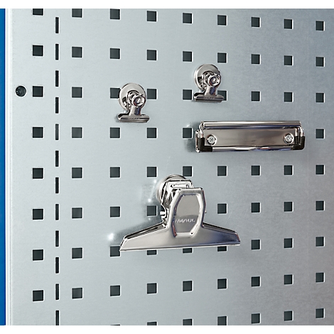 Nahaufnahme von Büroklammern und Klemmbrett an einer Metallwand mit quadratischen Löchern.