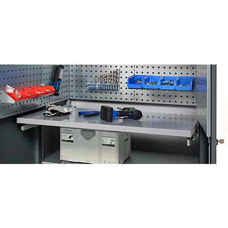 Tool wall with tools. Drills, screws, drawers, gloves. The focus is on the workbench and storage.