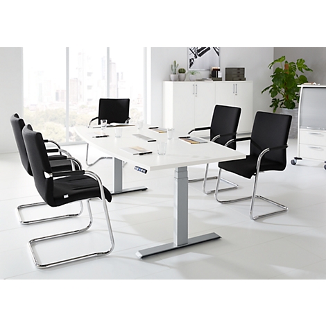 Sala de conferencias con mesa blanca, sillas negras y ventanas brillantes.