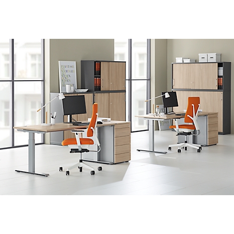 Office with two desks, chairs, cabinets. Orange chairs, wood look, silver frames. Monitors on the tables.