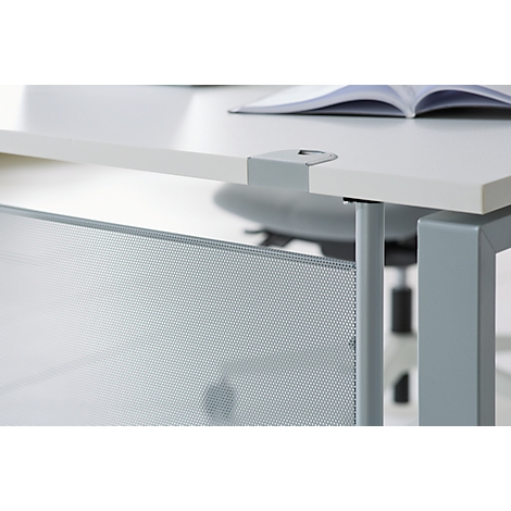 Close-up of a white desk with a silver metal frame. An open book lies on the surface. A perforated, metallic privacy screen is attached to the side.