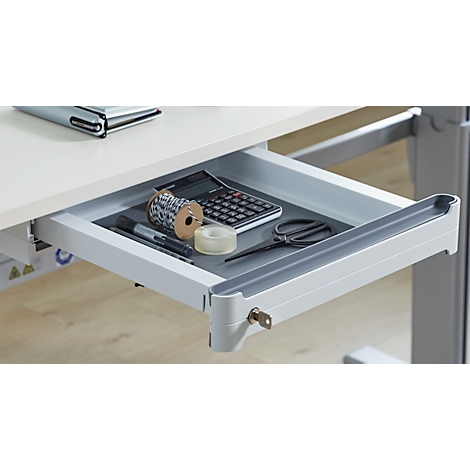 Eine geöffnete Schreibtischschublade mit Werkzeugen: eine Rolle Schnur, ein Taschenrechner, eine Schere, ein Klebeband und Stifte.