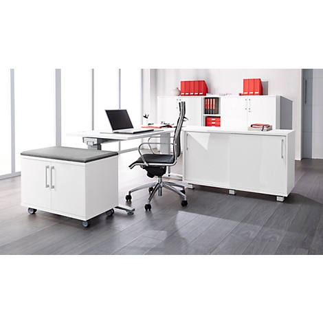 Office with white desk, chair, laptop, wall unit and roll container. Grey floor, lots of daylight.