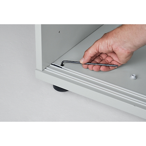 Close-up of a hand using an Allen wrench in a piece of furniture.