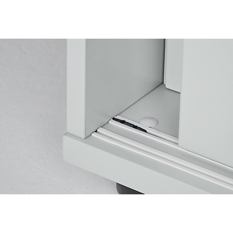 Close-up of a white cabinet corner with two parallel rails and a black gap.