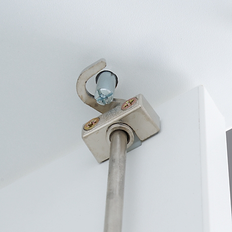 Close-up of a silver cabinet damper attached to a white cabinet door.