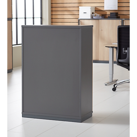 Grey cabinet in an office, light wood in the background. A window and a desk can also be seen.