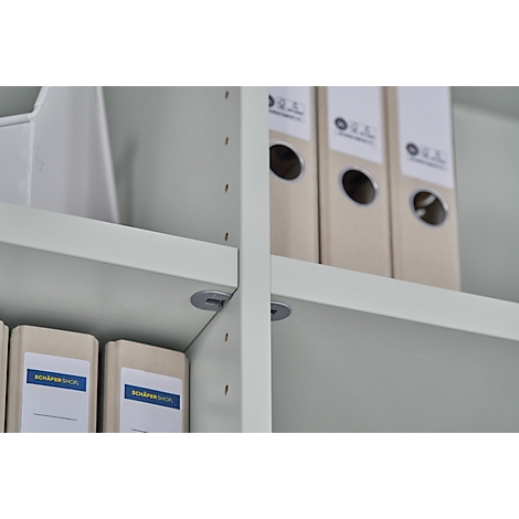 Close-up of a light grey shelf with file folders. The words "Schäfer Shop" can be read on the folders.