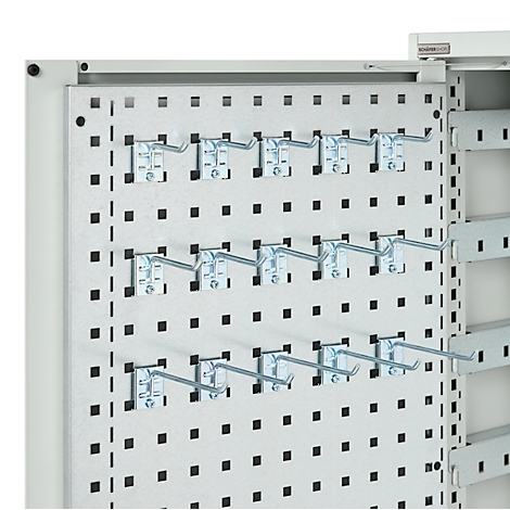 Metalen pegboard met haken. Vierkante gaten zijn gerangschikt op een grijze achtergrond, waarin metalen haken kunnen worden geplaatst.