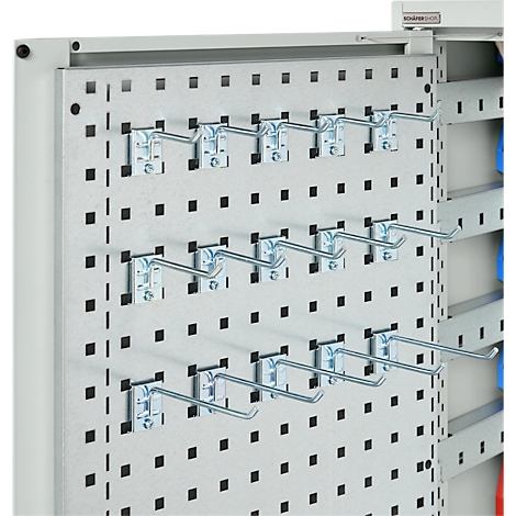 Metalen geperforeerd paneel met haken, daarachter een plank met gekleurde mappen.