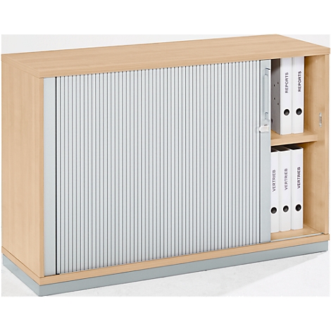 Wooden cabinet with slatted door, half open. Behind it, folders with the labels "Reports" and "Vertrieb".