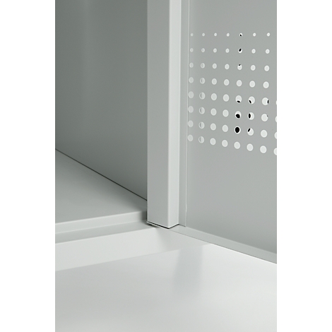 Vue de coin d'une armoire blanche, vue de détail. La porte comporte des trous circulaires.