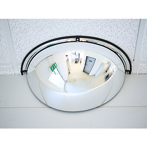 Un miroir de sécurité semi-circulaire est monté dans l'angle d'un faux plafond blanc.