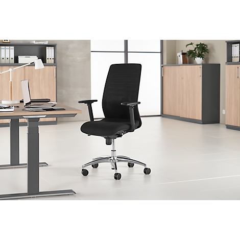 Black office chair with armrests and wheels in front of a desk and wall unit.