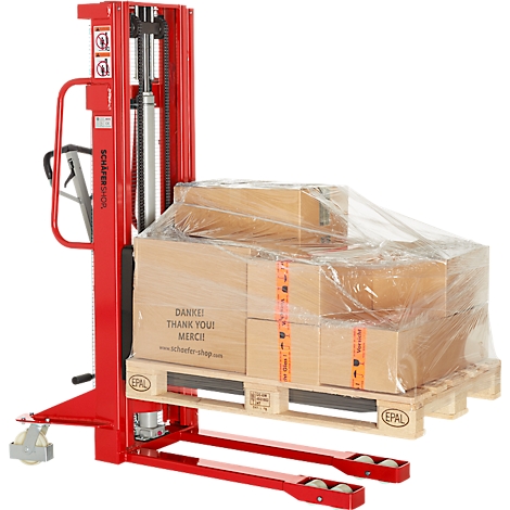 Red hand pallet truck with goods on a pallet. Pallets with boxes under foil, inscription 'Thank you!'.
