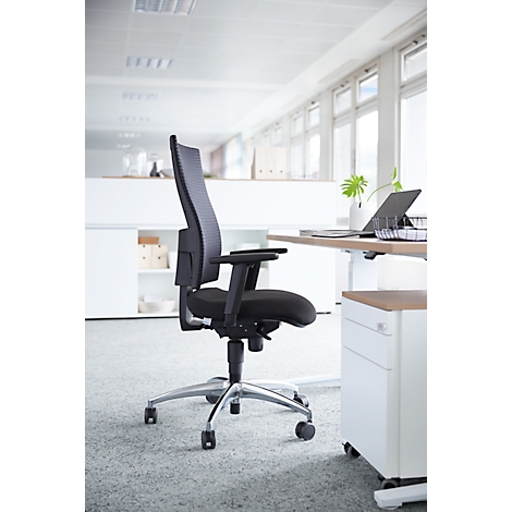 Black office chair at a desk in a bright office. The chair has a mesh back and castors. The desk is equipped with a laptop.