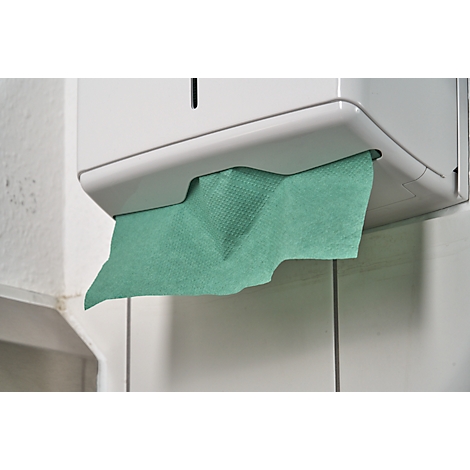 White paper towel dispenser with green paper protruding. Attached to a tiled wall.