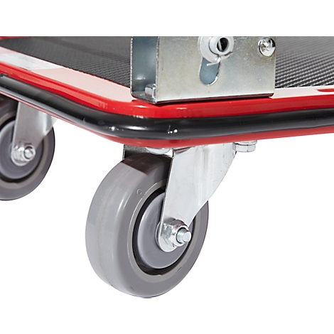 Close-up of two gray casters under a red transport cart. The casters have a metal frame.