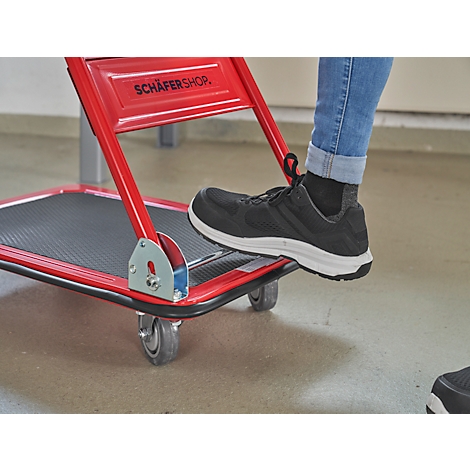 Close-up of red transport trolley, foot stepping to tilt. Inscription: Schäfer Shop.