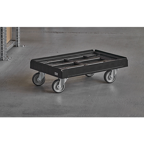 Black transport trolley with four wheels stands on gray floor. An empty shelf is seen in the background.