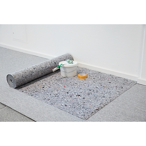 Eine Rolle Dämmvlies liegt auf einem Boden, daneben ein Farbeimer, eine Rolle und Klebeband.