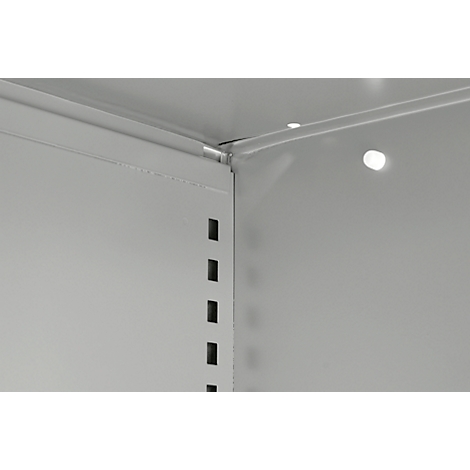 Coin métallique gris avec une série de trous rectangulaires et de reflets lumineux brillants.