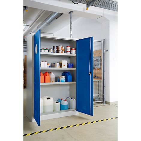 Armoire de sécurité bleue ouverte remplie de divers bidons, bouteilles et pots de peinture. Bandes d'avertissement jaunes et noires au sol.