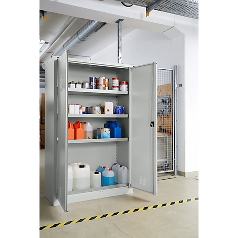 Armoire ouverte avec des produits chimiques dans une usine. Ruban d'avertissement jaune et noir sur le sol.