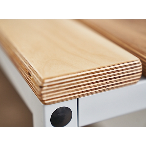Close-up of a light wood tabletop on a white frame. The layering of the wood is clearly visible.