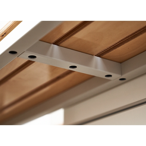 Close-up of wooden table underside with white metal supports fastened with dark screws.