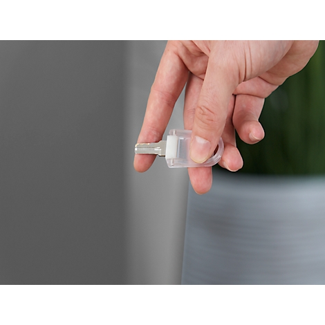 A hand holding a key. The key is in a transparent holder.