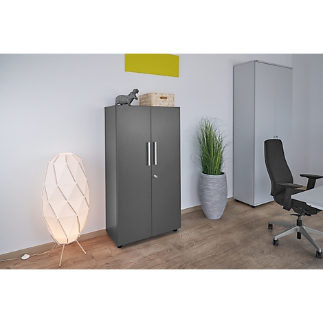 Dark grey filing cabinet in an office, next to a floor lamp and a plant.