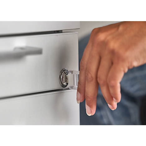 Una mano abre un cajón de un armario blanco. El cierre está enfocado.