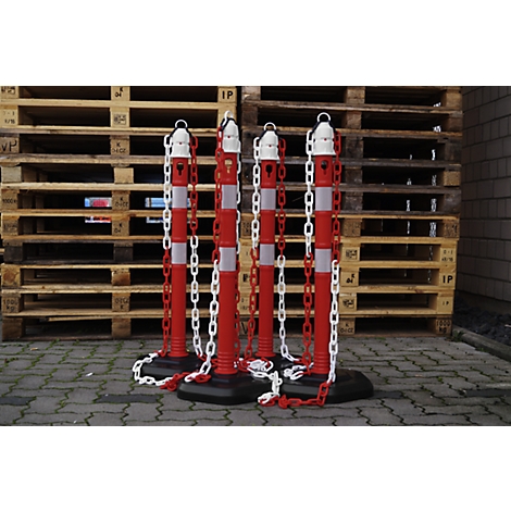 Four red and white bollards with chains in front of wooden pallets.