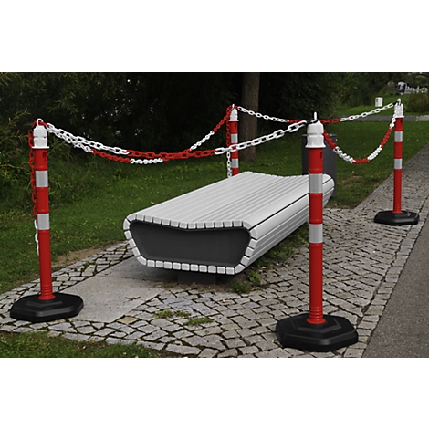 Modern park bench with barrier made of red and white posts and chains.