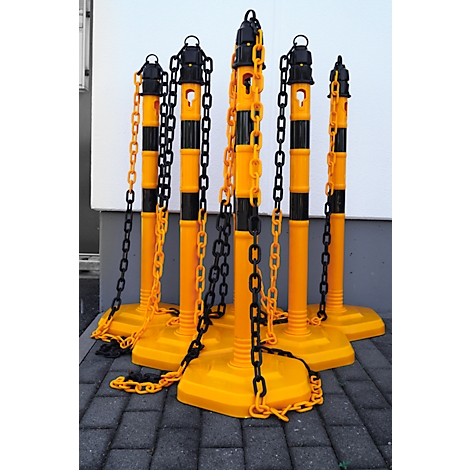 Yellow and black barrier posts with chains on paving stones.