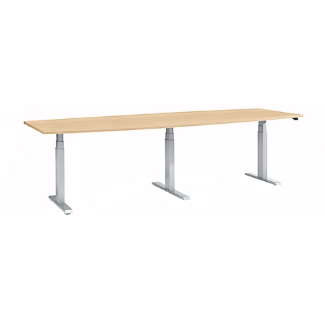 Long, height-adjustable desk with light brown tabletop and three silver legs.