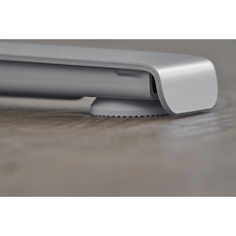 Close-up of a silver device. A rounded corner section rests on a small, grey foot with a ridged underside.