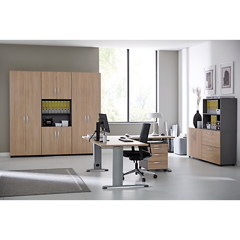 Office with wooden furniture. Desk with monitor, desk chair, filing cabinets. Window in the background.