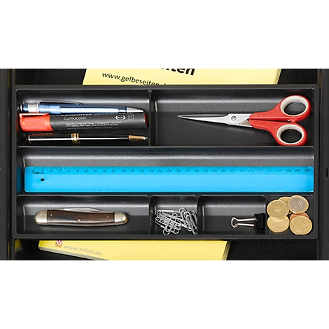 Black drawer filled with stationery: pens, scissors, ruler, coins, paper clips. Yellow note with text.