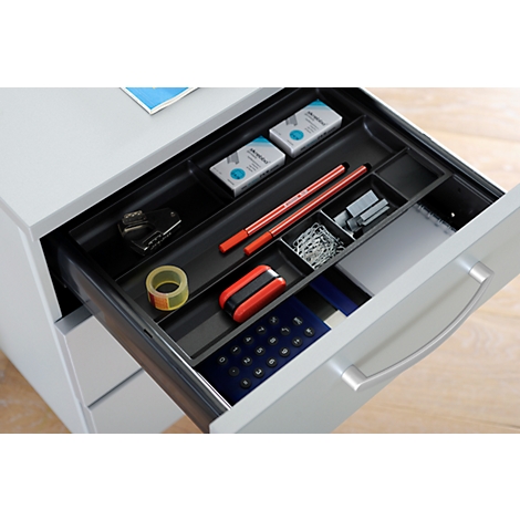 Drawer filled with office supplies, pens, stapler, paper clips and tape.