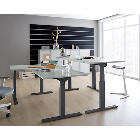 A bright, modern office space with height-adjustable desks and minimalist decor.