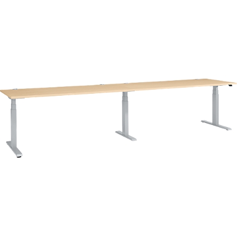 A long, height-adjustable desk. The light-colored tabletop is supported by silver legs.
